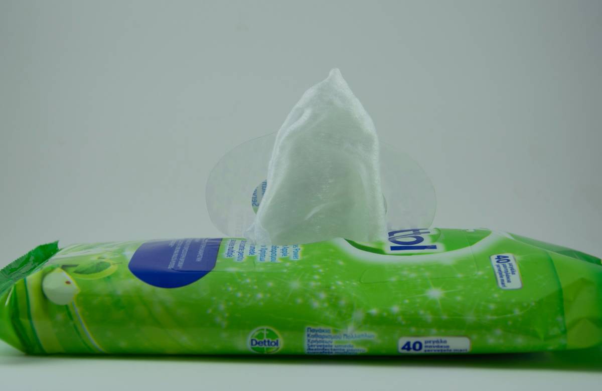 Woman using gentle wipes to wash body during travel, showing eco-friendly packaging